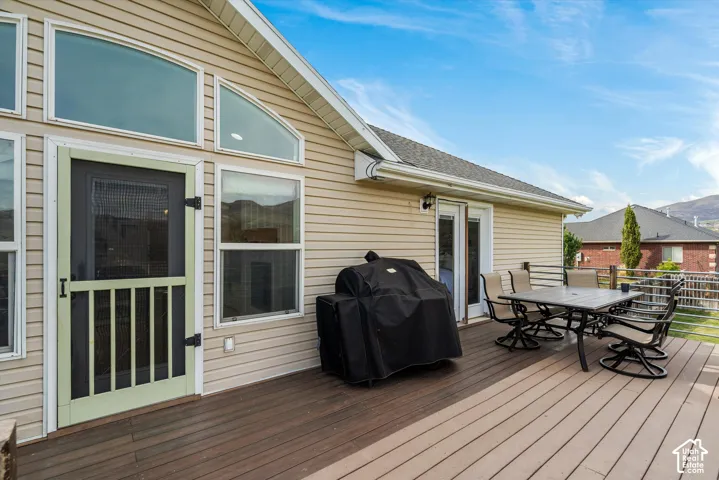 Exterior elevation featuring light-colored horizontal siding, arched windows, and a multi-level composite deck with metal railings