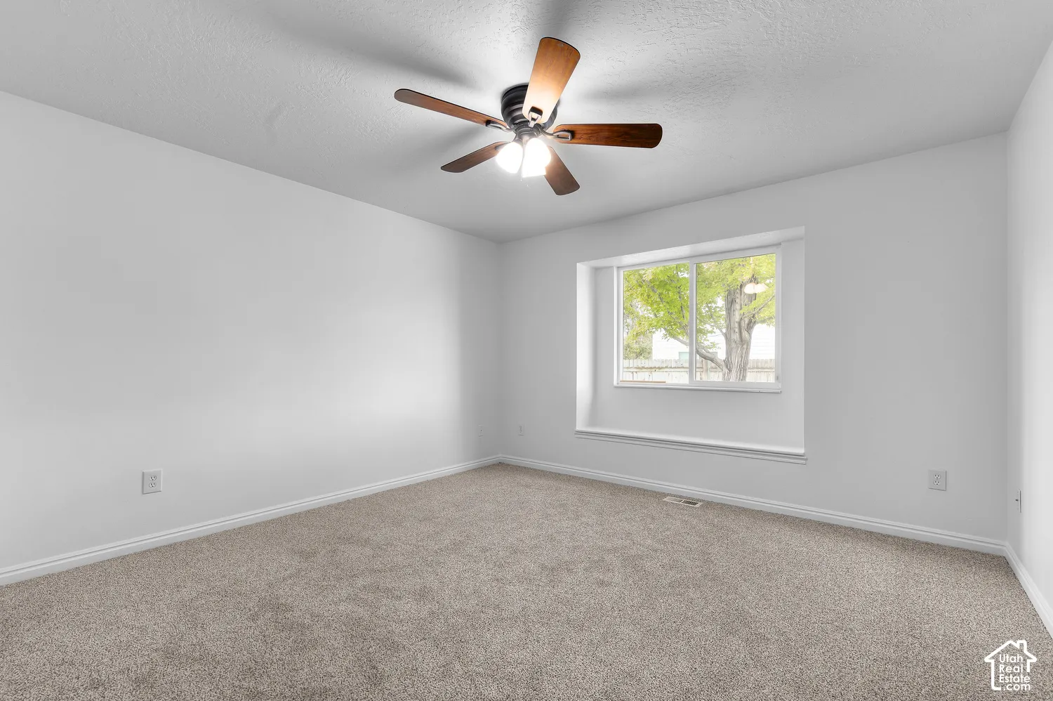 Room featuring neutral carpeting, a recessed window with a built-in sill, and a multi-blade ceiling fan with integrated lighting