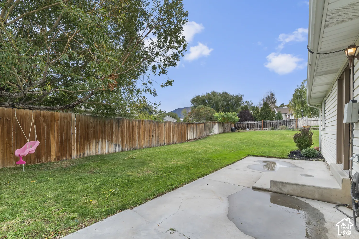 Backyard featuring a concrete patio, wood-style privacy fencing, and mature trees