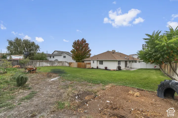 Expansive backyard featuring a large grass lawn and perimeter wood fencing