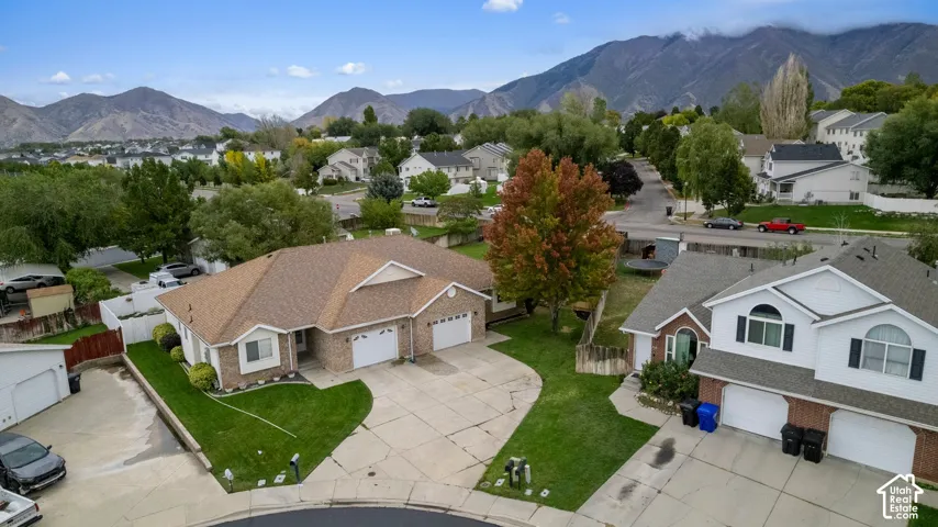 Single-story residence featuring a brick and siding exterior, attached  garage, concrete driveway, and expansive mountain backdrop