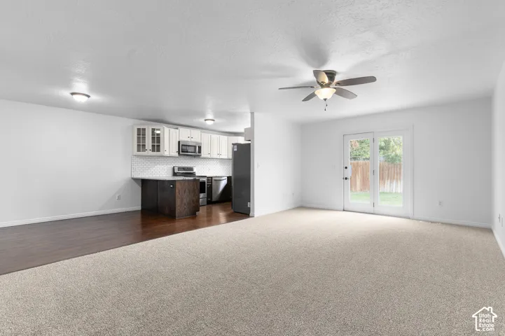 Open-concept kitchen featuring dark wood-finish cabinetry, white upper cabinets, a tiled backsplash, and recessed lighting