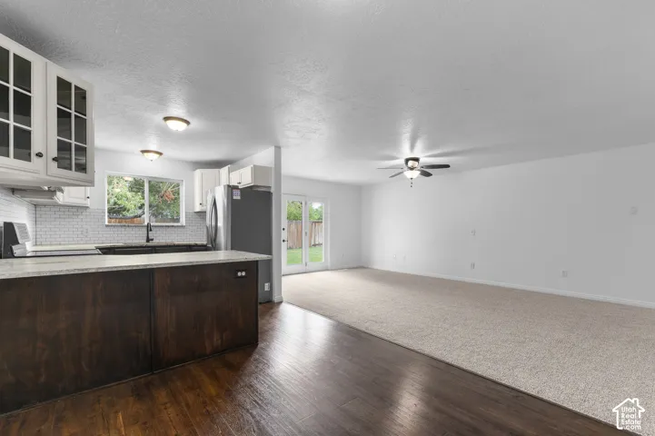 Kitchen featuring a stone-topped island, dark wood-finish cabinetry, white tiled backsplash, ceiling-mounted light fixtures, and glass-paneled double doors
