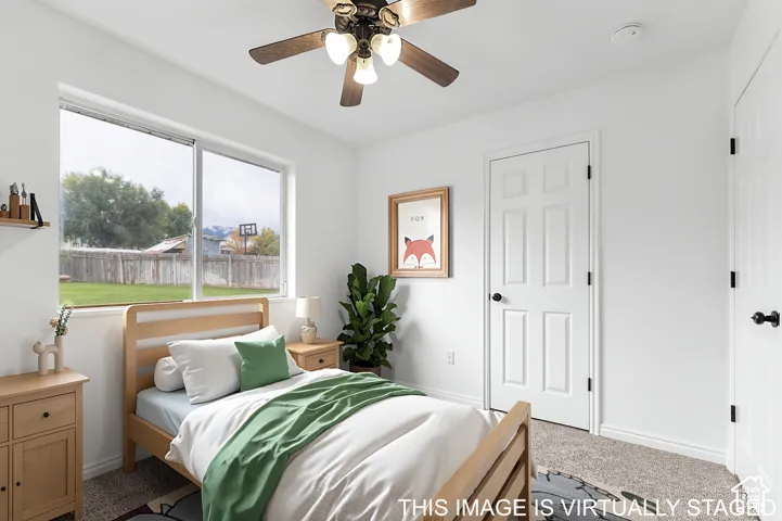 Room featuring a large sliding window, wall-to-wall carpeting, and a multi-blade ceiling fan with integrated lighting