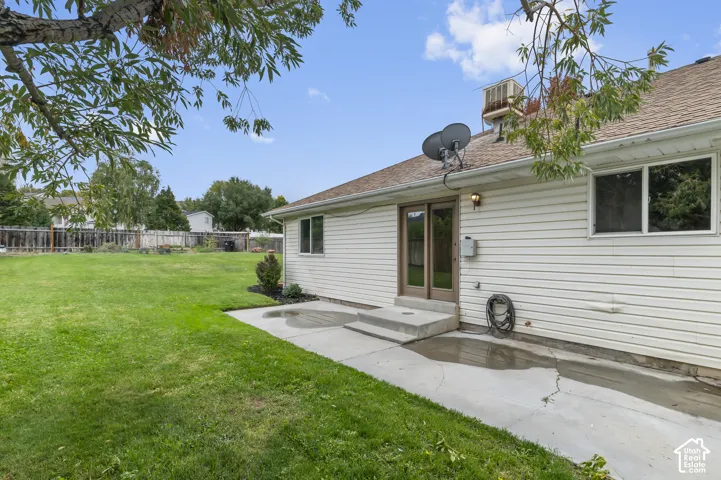 Expansive backyard featuring a concrete patio, sliding glass door entry, and mature trees