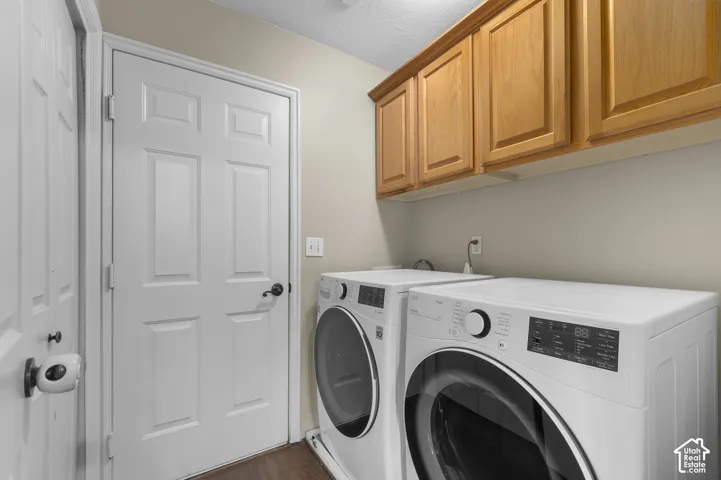 Laundry area featuring wood-finish cabinetry, white paneled doors, and dark-toned flooring