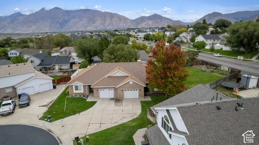 Single-story brick and siding exterior featuring an attached garage, concrete driveway, and mountain backdrop