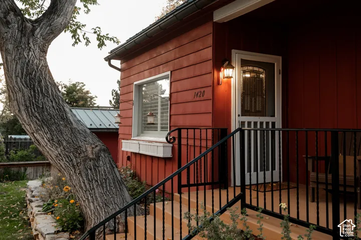 Red siding exterior featuring a covered porch with black metal railings and steps
