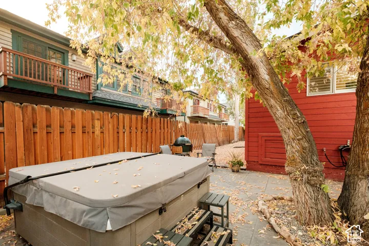 Private outdoor patio space featuring a hot tub, stone paver flooring, and mature trees