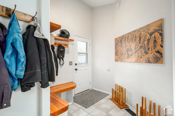 Entryway featuring light-toned wall paint, tiled flooring, a white paneled door with a window, and built-in wood shelving and bench seating