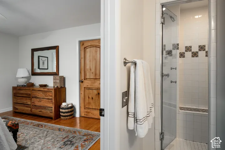 Shower with glass enclosure, white square tile, and decorative accent tile