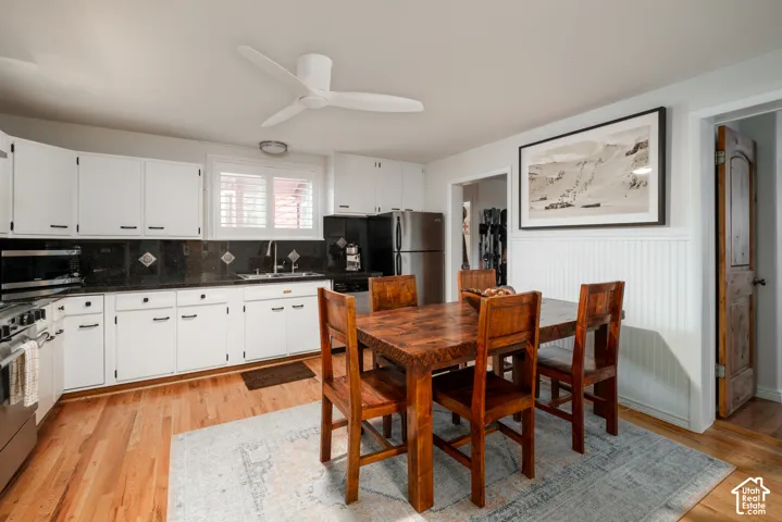 Kitchen with white cabinetry, dark countertops, hardwood flooring, and a ceiling fan