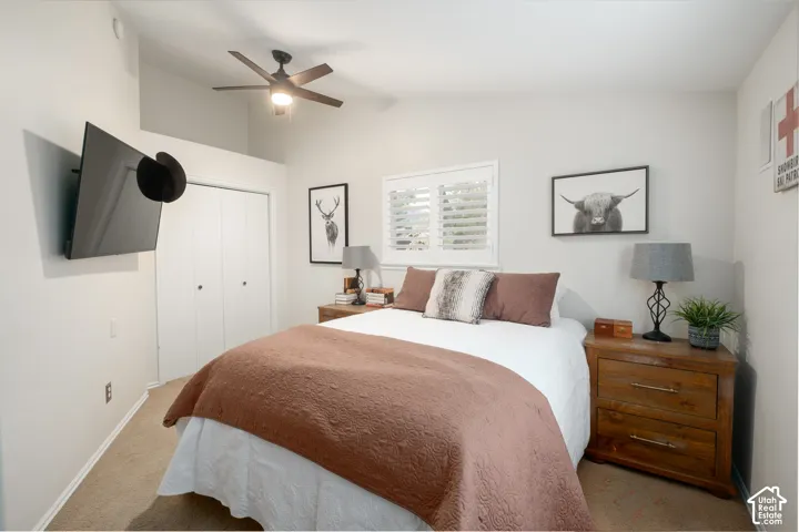 Vaulted ceiling with a ceiling fan, window with plantation shutters, dual bi-fold closet doors, and wall-mounted television