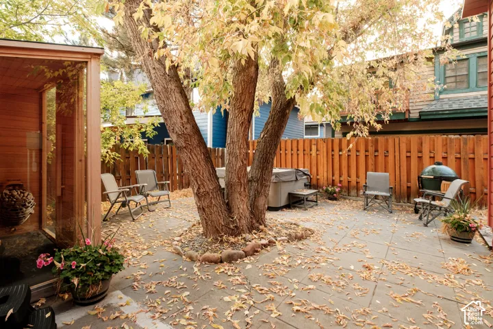 Patio area featuring large mature trees, privacy fencing, and a built-in outdoor structure