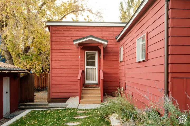 Red-sided exterior with white trim windows and a covered entry