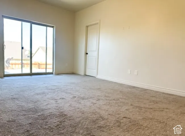 Room featuring neutral-toned carpeting, sliding glass doors, and a six-panel interior door