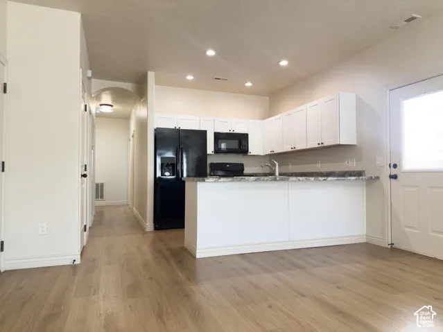 Kitchen featuring white shaker-style cabinetry, a stone-finish countertop, black built-in appliances, recessed lighting, and wood-finish flooring