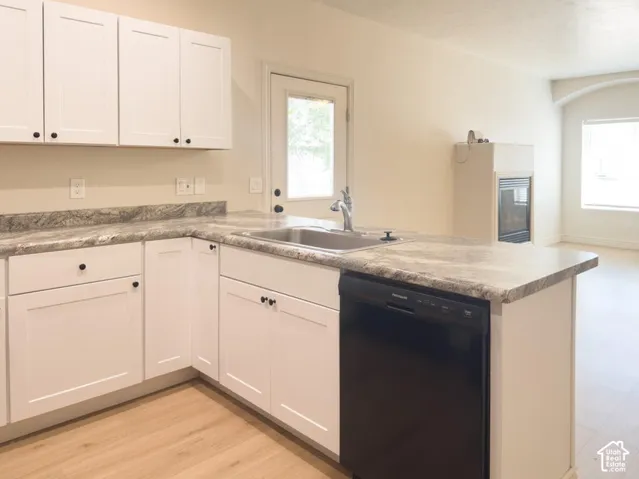 Kitchen featuring white shaker-style cabinetry, stone-patterned laminate countertops, stainless steel undermount sink, built-in dishwasher, and wood-finish flooring