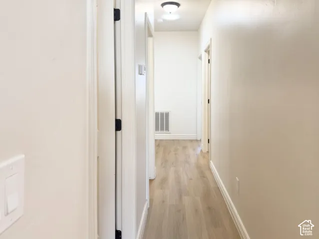 Hallway featuring wood-finish flooring, smooth-finish walls, and ceiling-mounted flush light fixtures