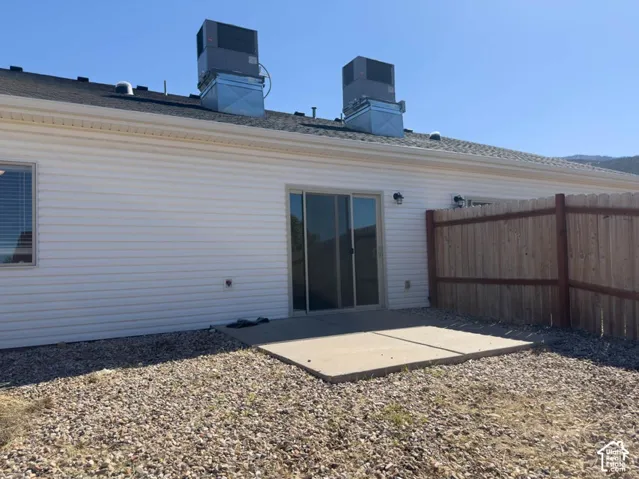 Exterior featuring white horizontal siding, a concrete patio, and a wood privacy fence