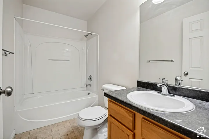 Bathroom featuring a composite vanity with an integrated basin, stone-finish countertop, full-width wall mirror, and a white acrylic tub-shower surround