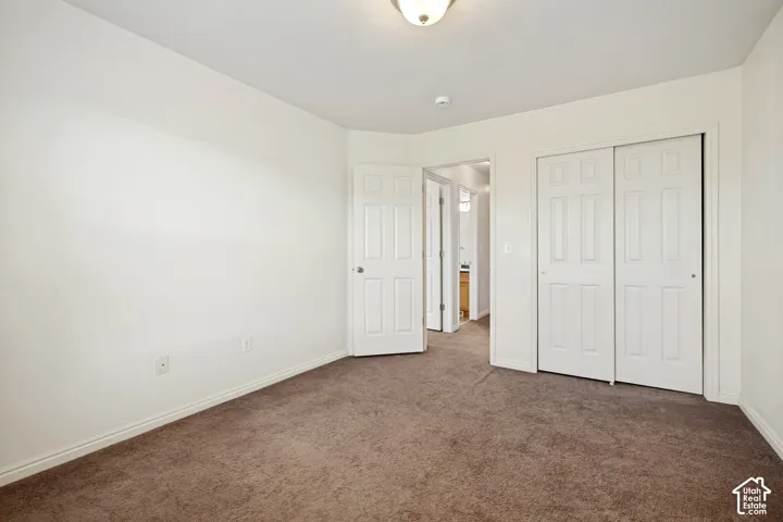 Room featuring neutral wall tones, carpeted flooring, a two-panel interior door, and a sliding-panel closet with six-panel detailing