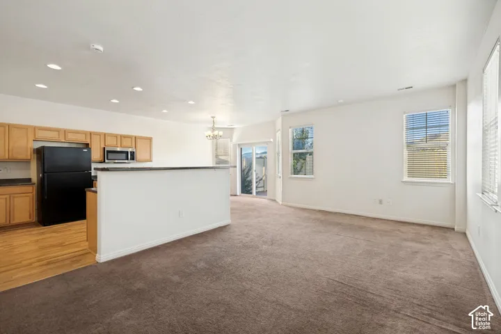 Kitchen featuring wood cabinetry, laminate countertops, and built-in appliances including a microwave, complemented by recessed lighting, carpeted flooring, and sliding glass doors