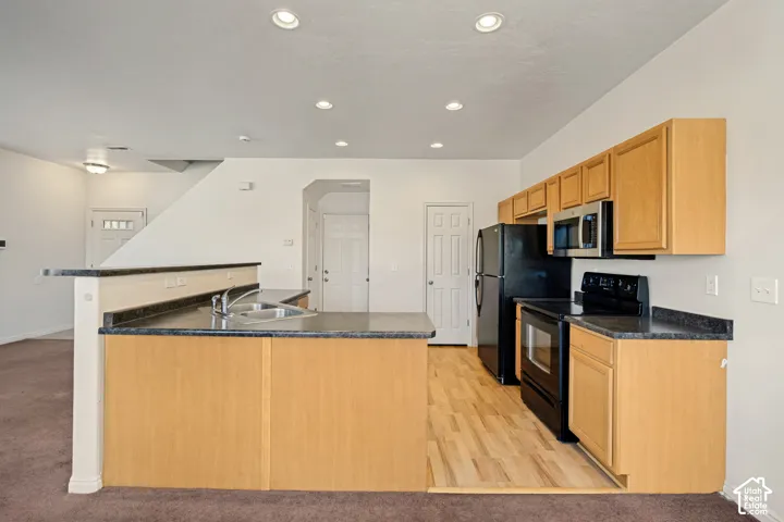 Kitchen featuring flat-panel wood cabinetry, dark laminate countertops, recessed lighting, and wood-finish flooring