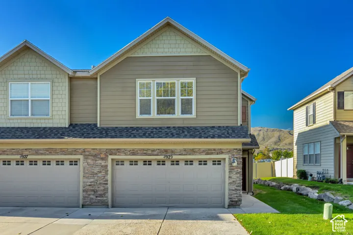 Exterior featuring horizontal siding, decorative shingle accents, stone-veneer facade, multi-car garage, and asphalt shingle roof