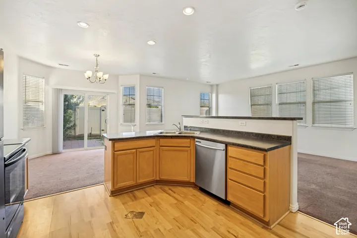 Kitchen featuring wood-finish cabinetry, dark solid-surface countertops, stainless steel dishwasher, recessed lighting, and wood-finish flooring