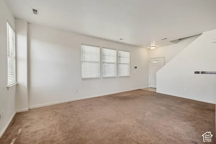 Neutral-toned carpeting and multiple windows with horizontal blinds featuring ample natural light