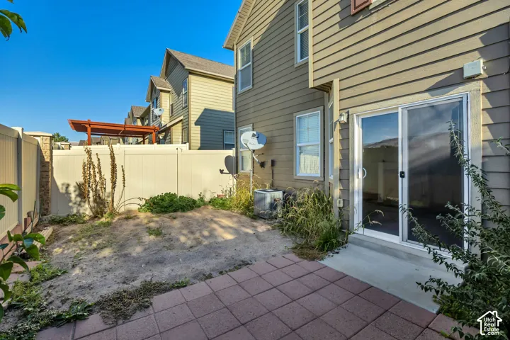 Private backyard featuring a paved stone patio, horizontal siding exterior, and a solid perimeter privacy fence