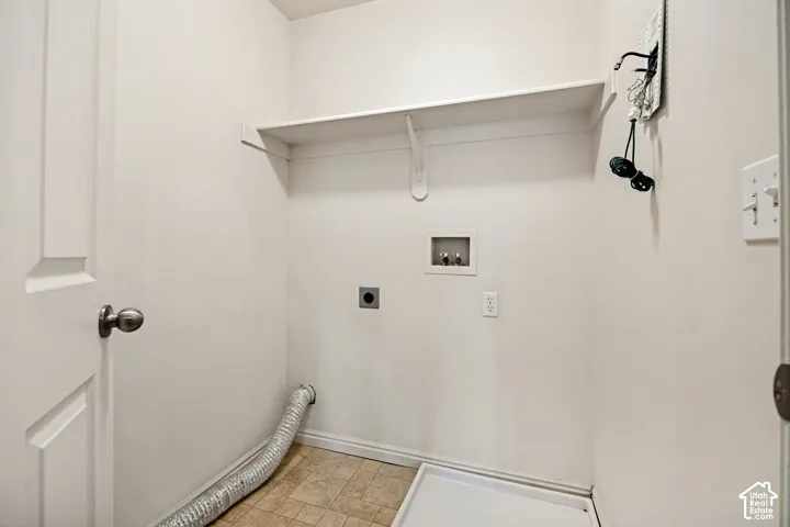 Dedicated utility area featuring tile flooring, built-in shelving, and washer and dryer hookups