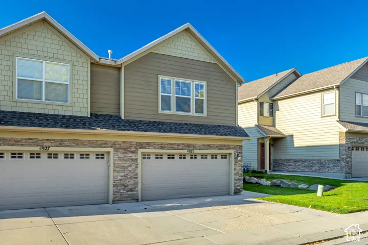 Multi-level exterior featuring horizontal lap siding, shake-shingle accents, stone veneer lower facades, and multi-car garages