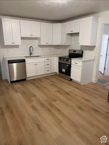Kitchen featuring white Shaker-style cabinetry, quartz countertops, stainless steel appliances, and wood-finish flooring
