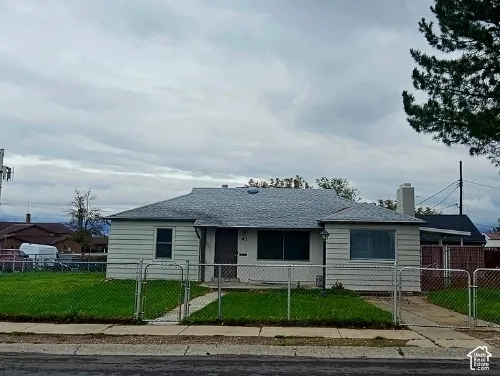 Single-story residence featuring light-colored horizontal siding, a composition shingle roof, exterior masonry chimney, and an attached side carport