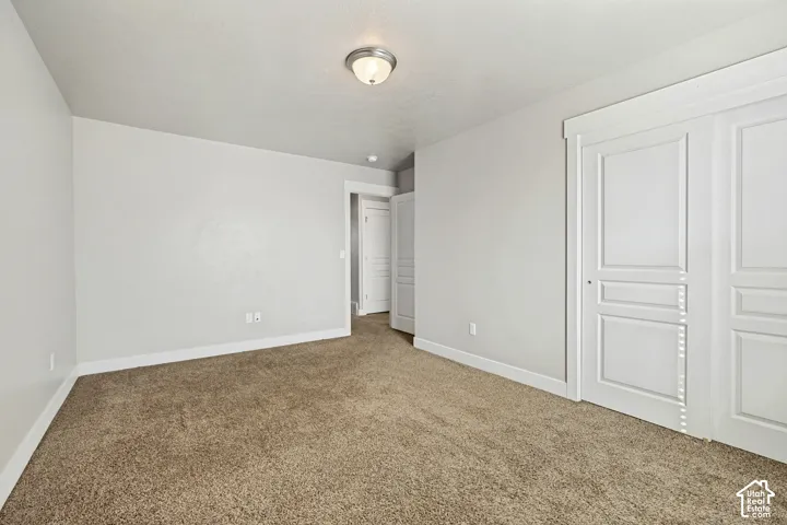Neutral-toned interior space featuring plush carpeting, recessed ceiling lighting, and crisp white paneled doors with substantial trim