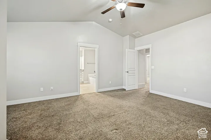 Vaulted ceilings, neutral wall color, carpeted flooring, and a ceiling fan with integrated lighting