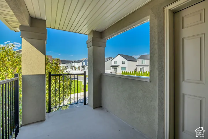 Covered balcony featuring concrete flooring, stucco-finished support columns, and black metal railings