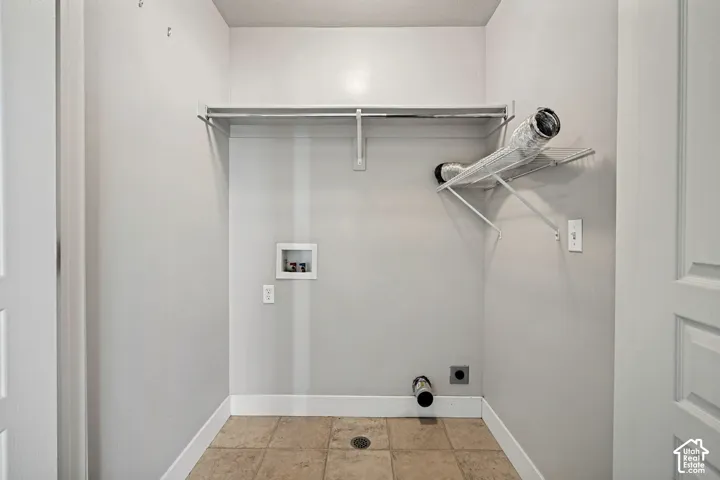 Utility area featuring tile flooring, built-in wire shelving, and dedicated plumbing connections