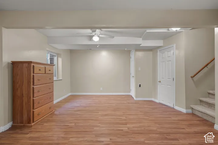 Interior space featuring wood-finish flooring, recessed ceiling lighting, a white ceiling fan, and carpeted stairs with a handrail