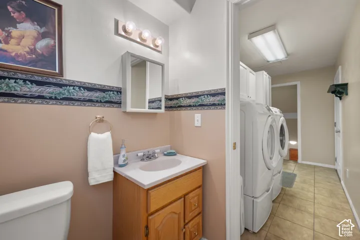 Bathroom vanity with a white countertop and oval basin, medicine cabinet, three-light fixture, tile flooring, and built-in laundry cabinetry