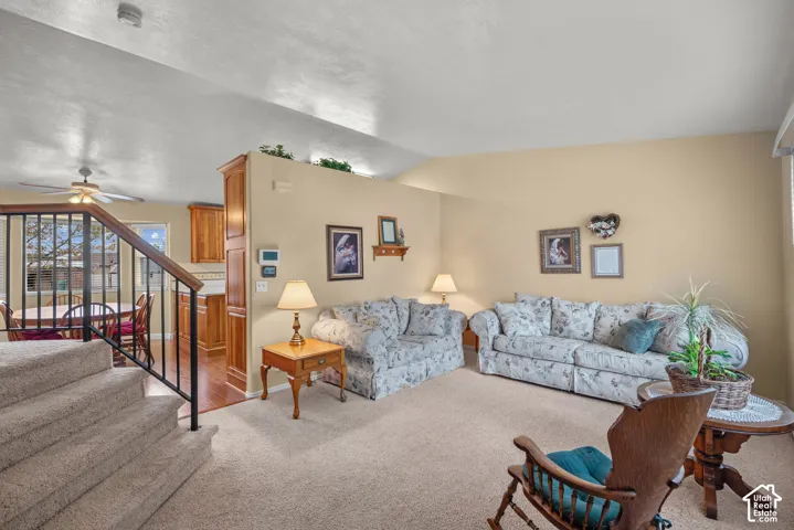 Vaulted ceilings, carpeted flooring, and metal railing staircase featuring wooden handrail