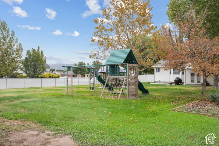 Expansive backyard featuring a large grass lawn, mature trees, and perimeter vinyl fencing