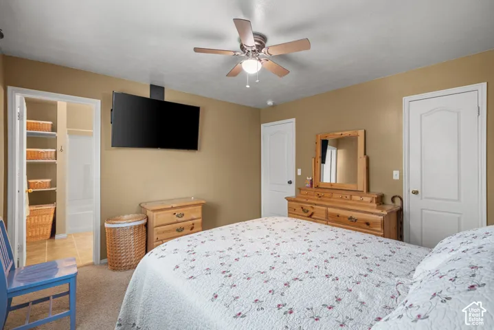 Neutral-toned room featuring a ceiling fan with integrated lighting, carpeted flooring, and two interior doors with arched-panel detailing