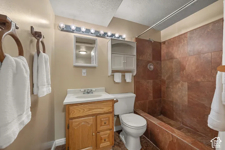 Bathroom featuring a wood vanity with a white countertop, inset sink, tile-surround bathtub, built-in cabinetry, and multi-bulb wall lighting