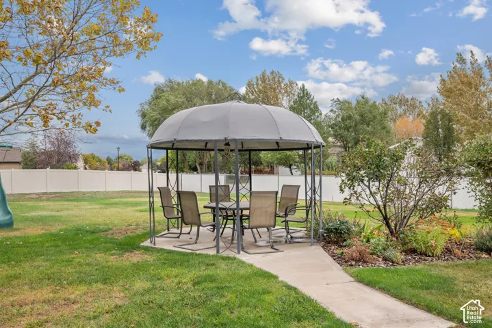 Backyard featuring a concrete patio, perimeter vinyl fencing, and mature trees
