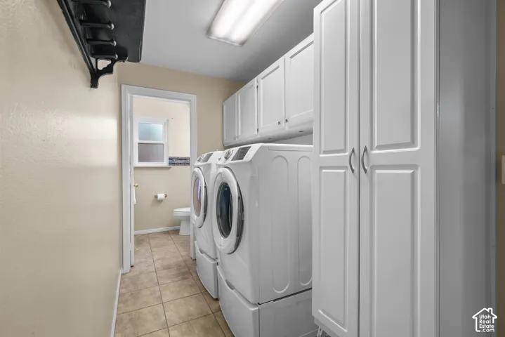 Laundry room featuring tile flooring, white cabinetry with overhead storage, floor-to-ceiling built-in pantry, and recessed lighting
