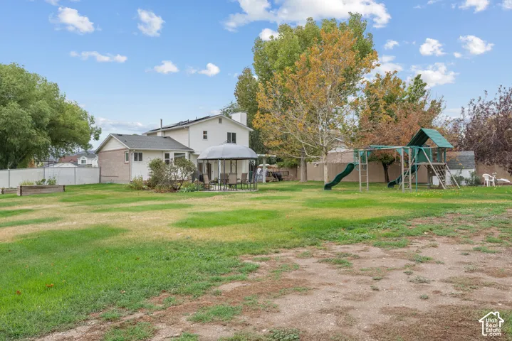 Expansive backyard featuring a large grass lawn, mature trees, privacy fencing, and a permanent garden bed