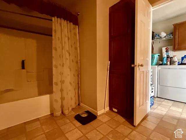 Full-height wood-finish storage cabinetry and a tub-shower combination with integrated surround